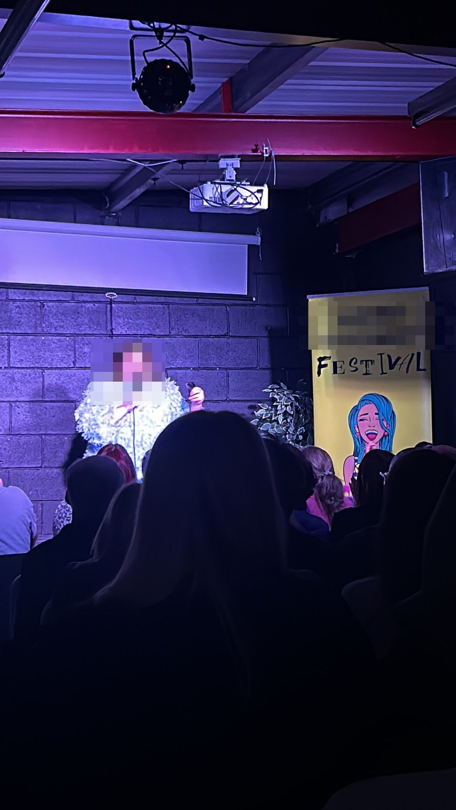 A stand-up comedian performing on stage at a comedy festival venue